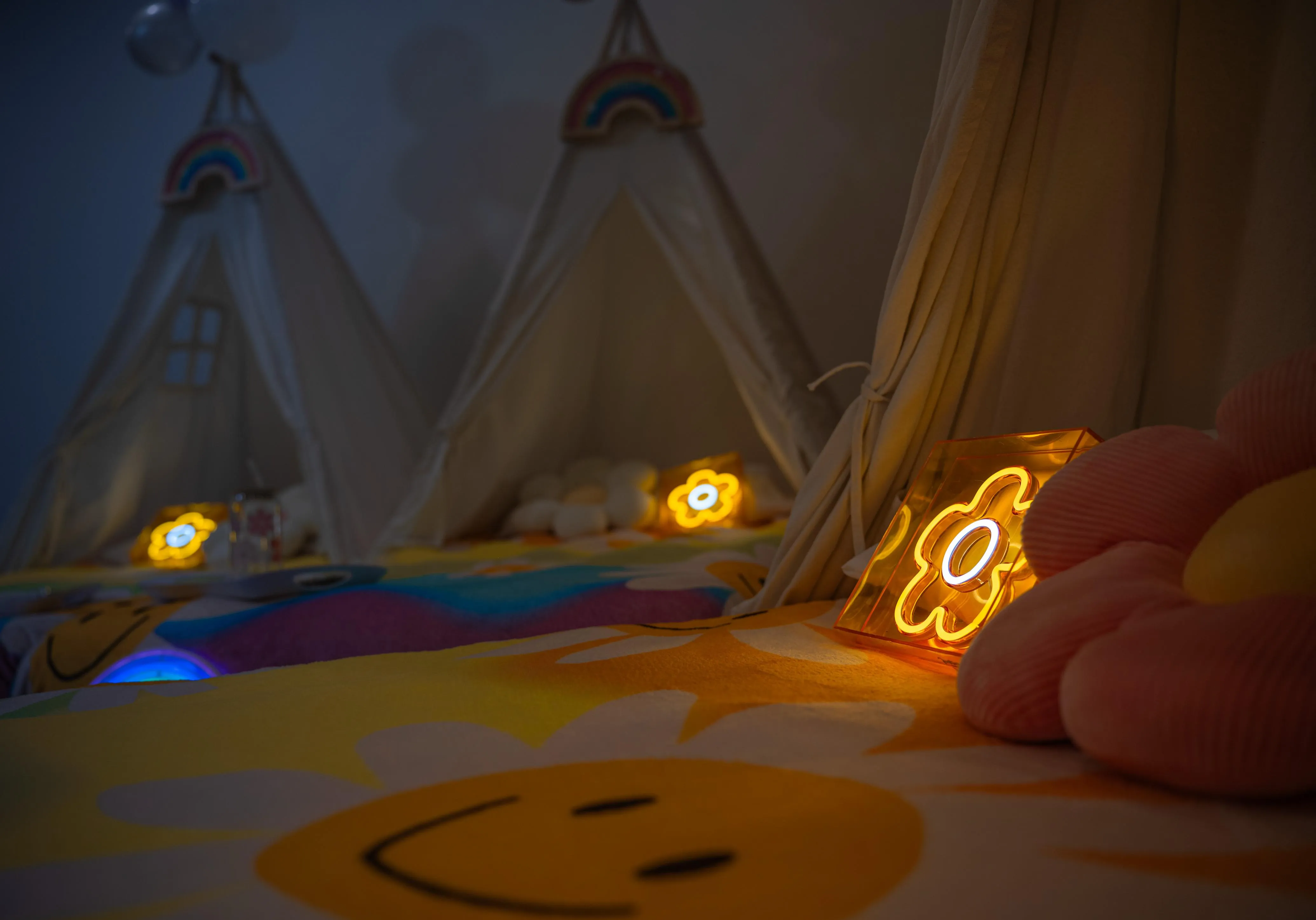 Three cream teepees arranged with floral bedding, glowing flower lights and rainbow details.